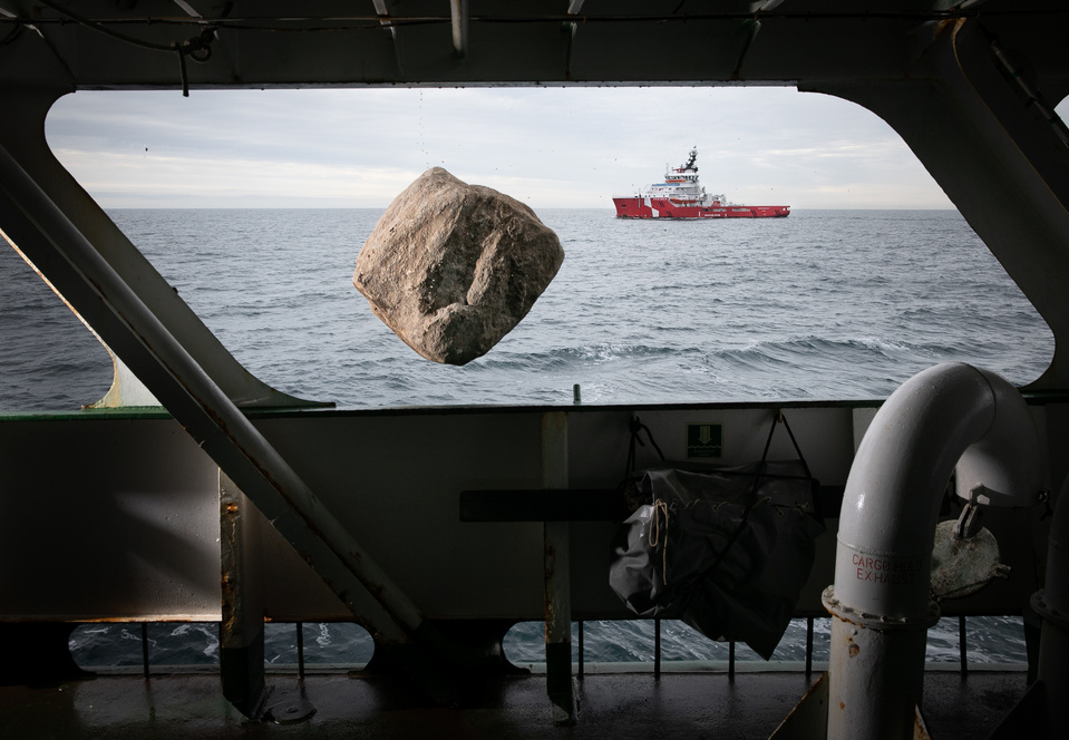 a shot from a window in a boat with a rock hovering over open water