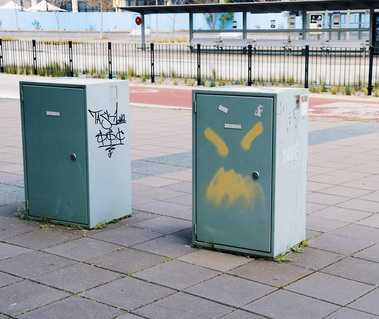 A crude angry face tagged onto an electrical box. 