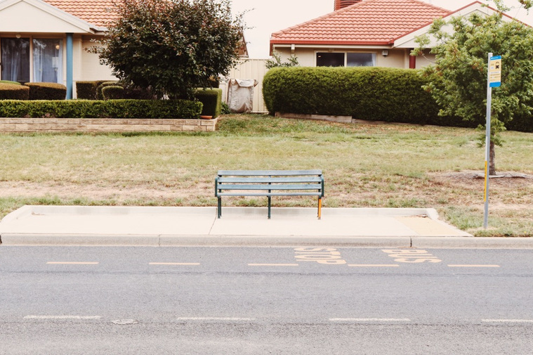A simple park bench functioning as a bus stop. 