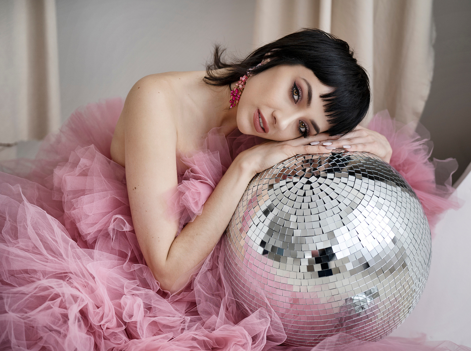 model leaning on a glitter ball wearing a pink tulle dress