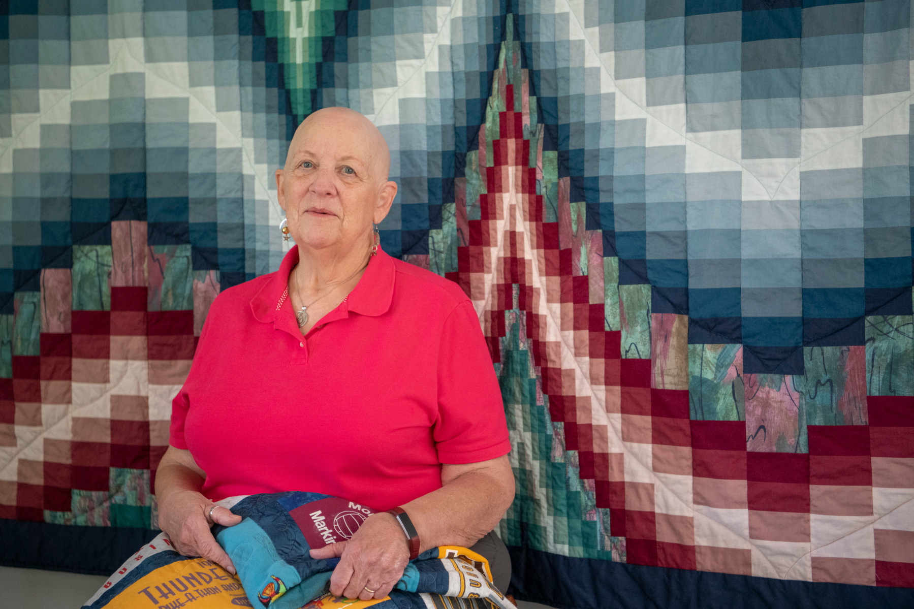 Jeannette Fromm, 75, of Centerville, Ohio, sits in front of a quilt she made, while holding another quilt, made for her husband out of his college t-shirts, on Sept. 13, 2020. Jeannette began sewing when she was in sixth grade, she made herself a pair of