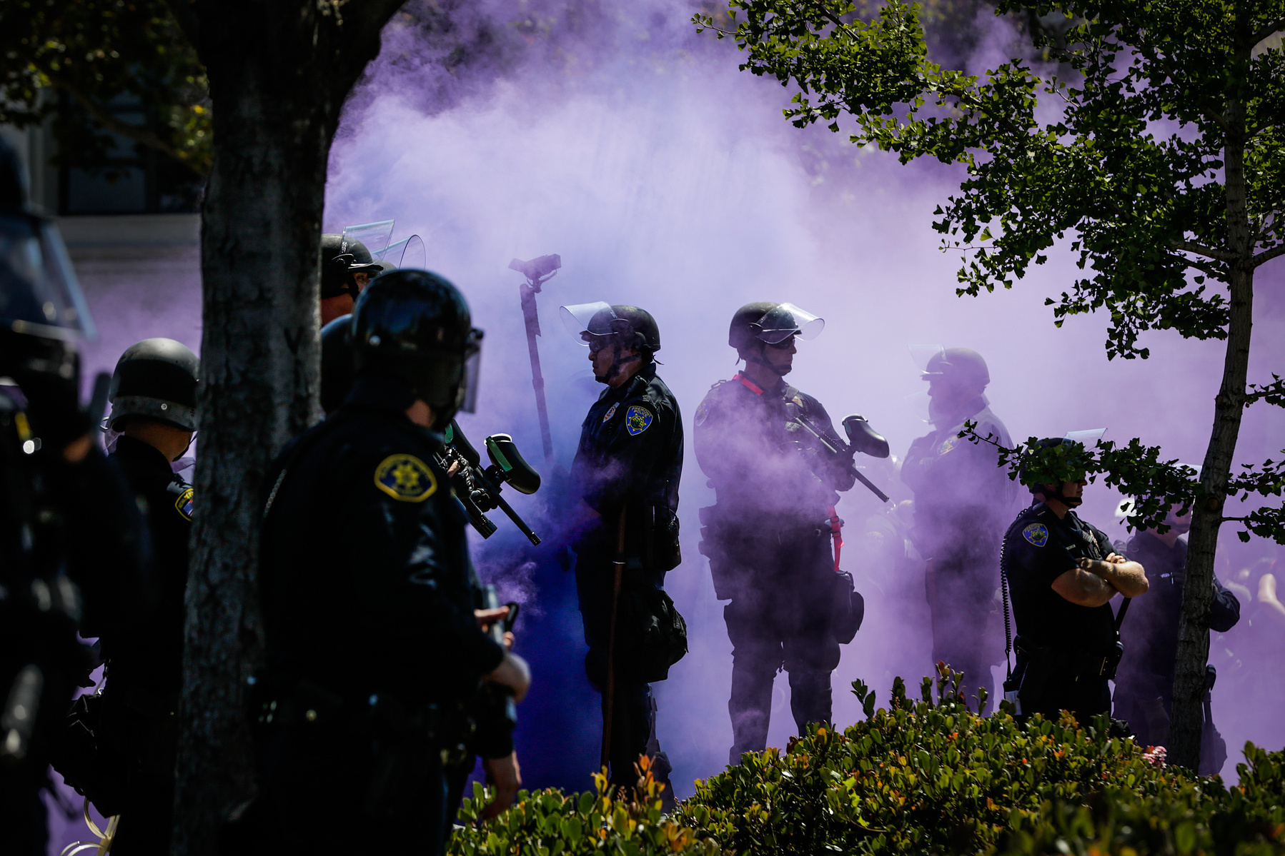 Police officers are covered in a purple smokebomb haze on Martin Luther King Jr. Way and Allston Way during a protest in Berkeley, Calif., on Sunday, August 27th, 2017.