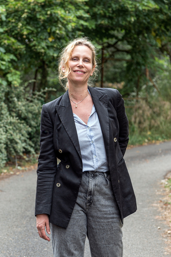 a blond woman standing on a road in the forest in France, Marie Garel Weiss, french female movie director