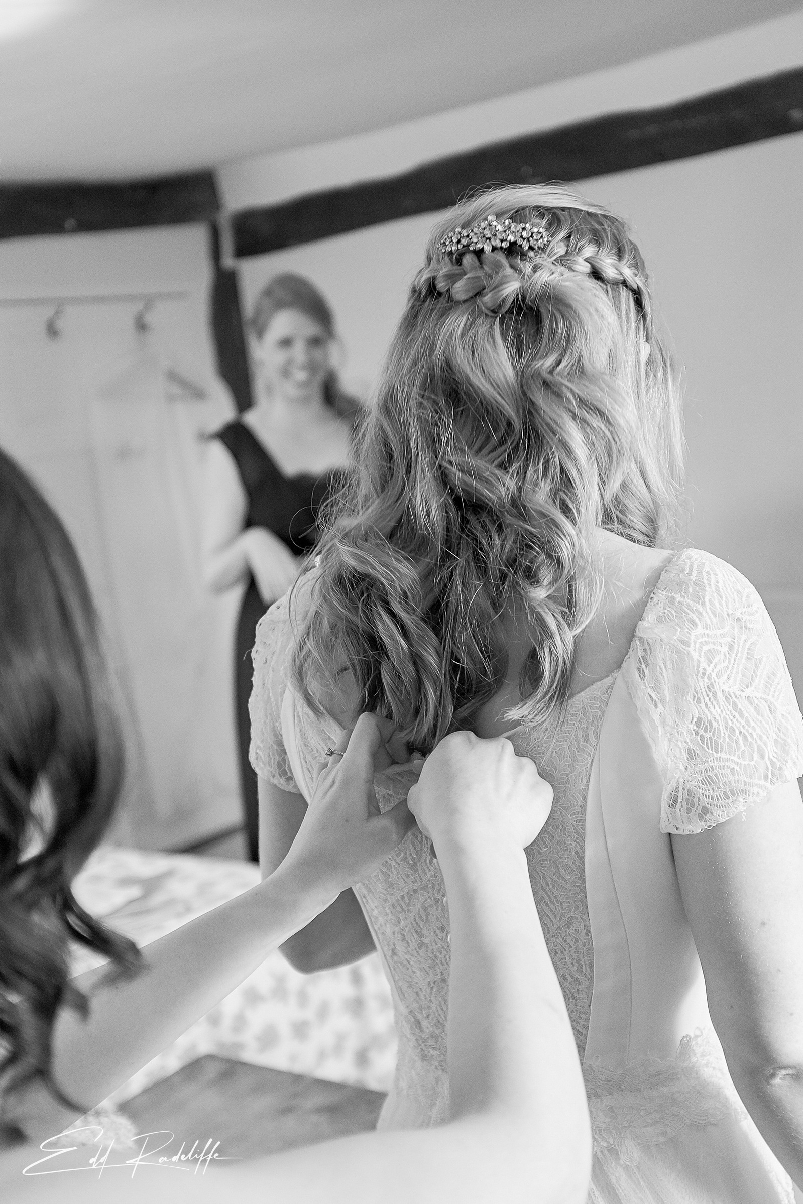 View of the Bride from behind while someone zips her dress up at the Reid Rooms, Chelmsford for Edd Radcliffe Photography - documentary style wedding photography