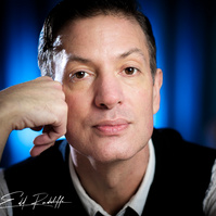 Close-up portrait of a thoughtful man resting his chin on his hand, wearing a vest and tie, with a blue-lit background. Perfect for creative profiles, artistic branding, or professional use.