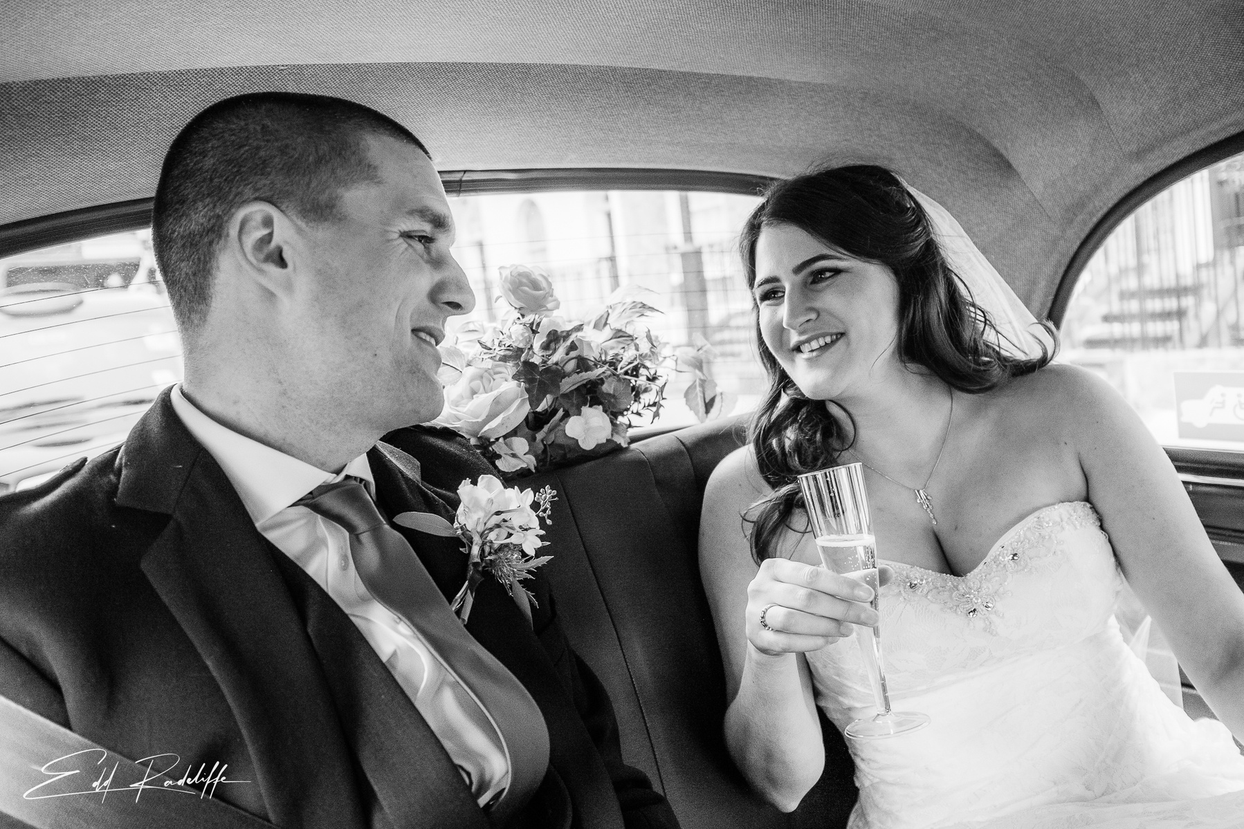 Bride and Groom share a smile in the back of the wedding car on way to Chiswell Street Dining Rooms, Islington for Edd Radcliffe Photography - documentary style wedding photography