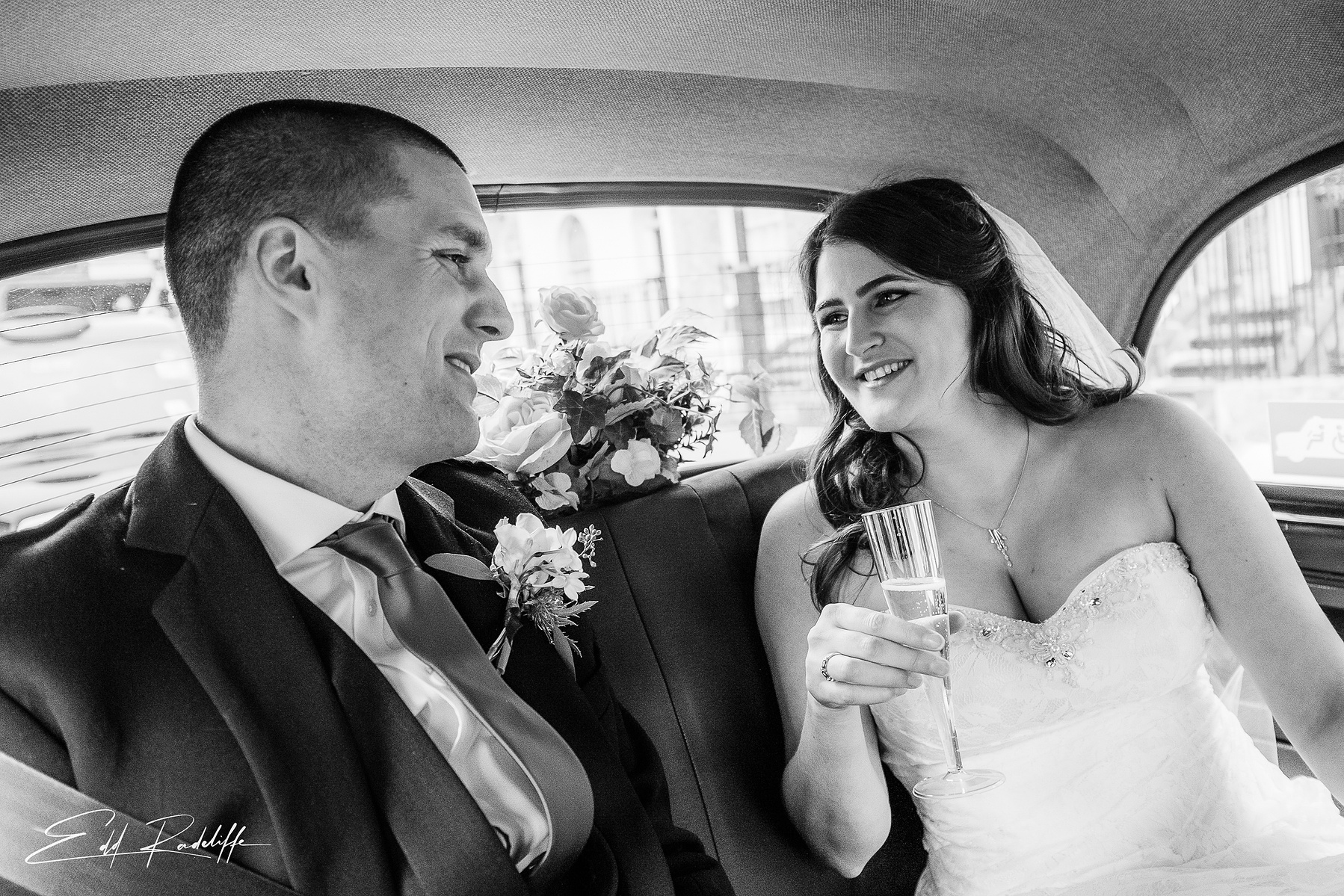 Bride and Groom share a smile in the back of the wedding car on way to Chiswell Street Dining Rooms, Islington for Edd Radcliffe Photography - documentary style wedding photography