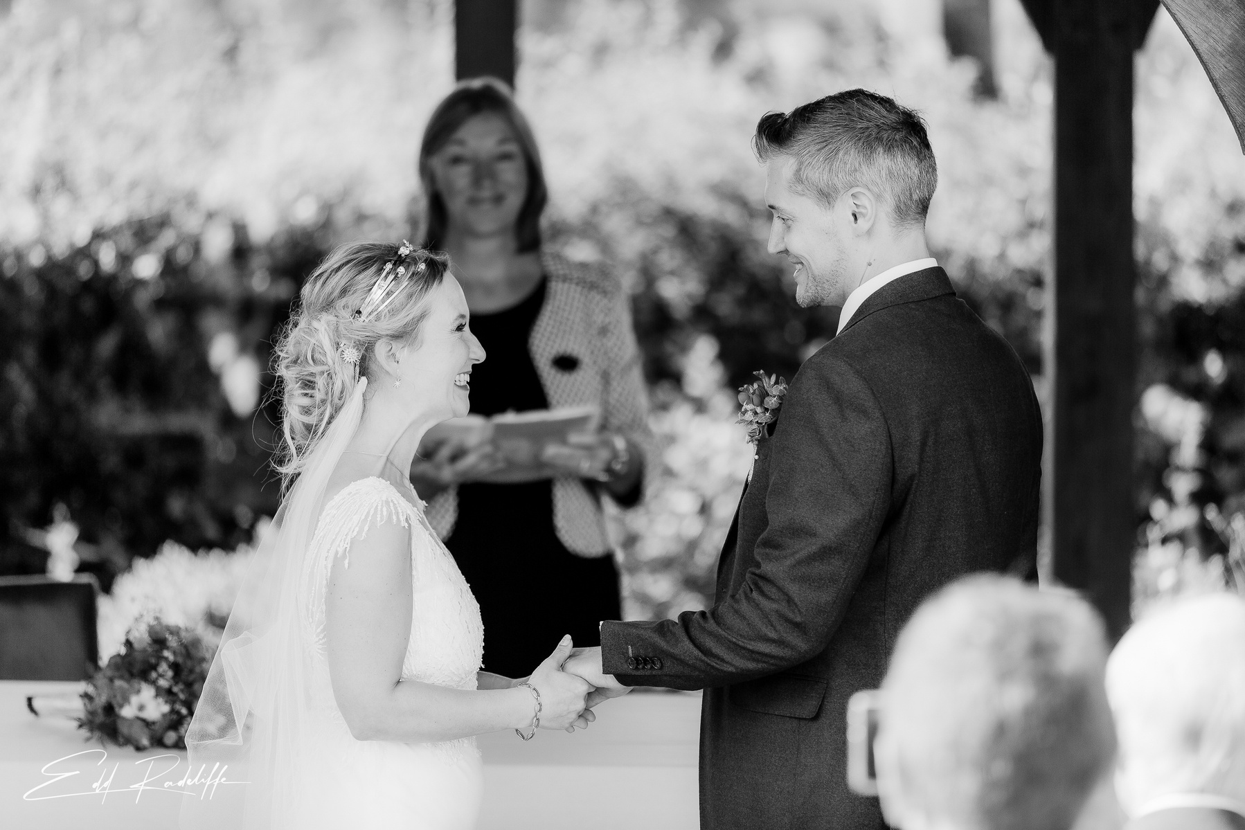 Bride and Groom exchange wedding vows while holding hands and smiling at Groomes in Hampshire for Edd Radcliffe Photography - documentary style wedding photography