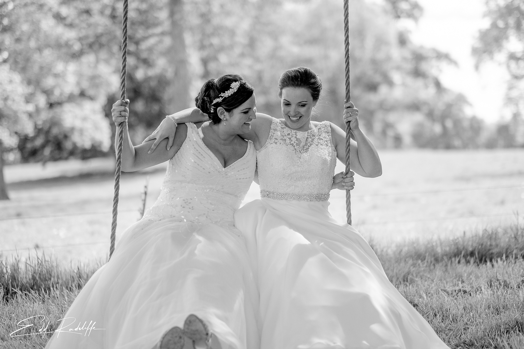 Brides with their arms around each other on a swing at Carlton Towers, Yorkshire for Edd Radcliffe Photography - documentary style wedding photography