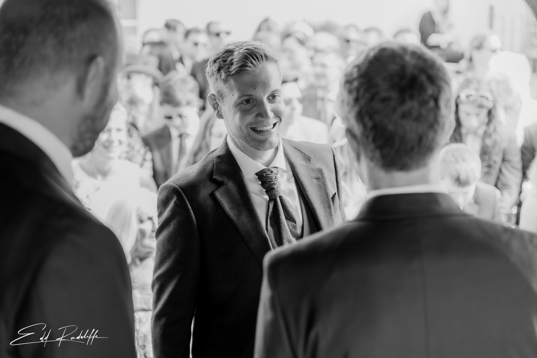 Groom smiles at best man while waiting at alter at Groomes in Hampshire for Edd Radcliffe Photography - documentary style wedding photography