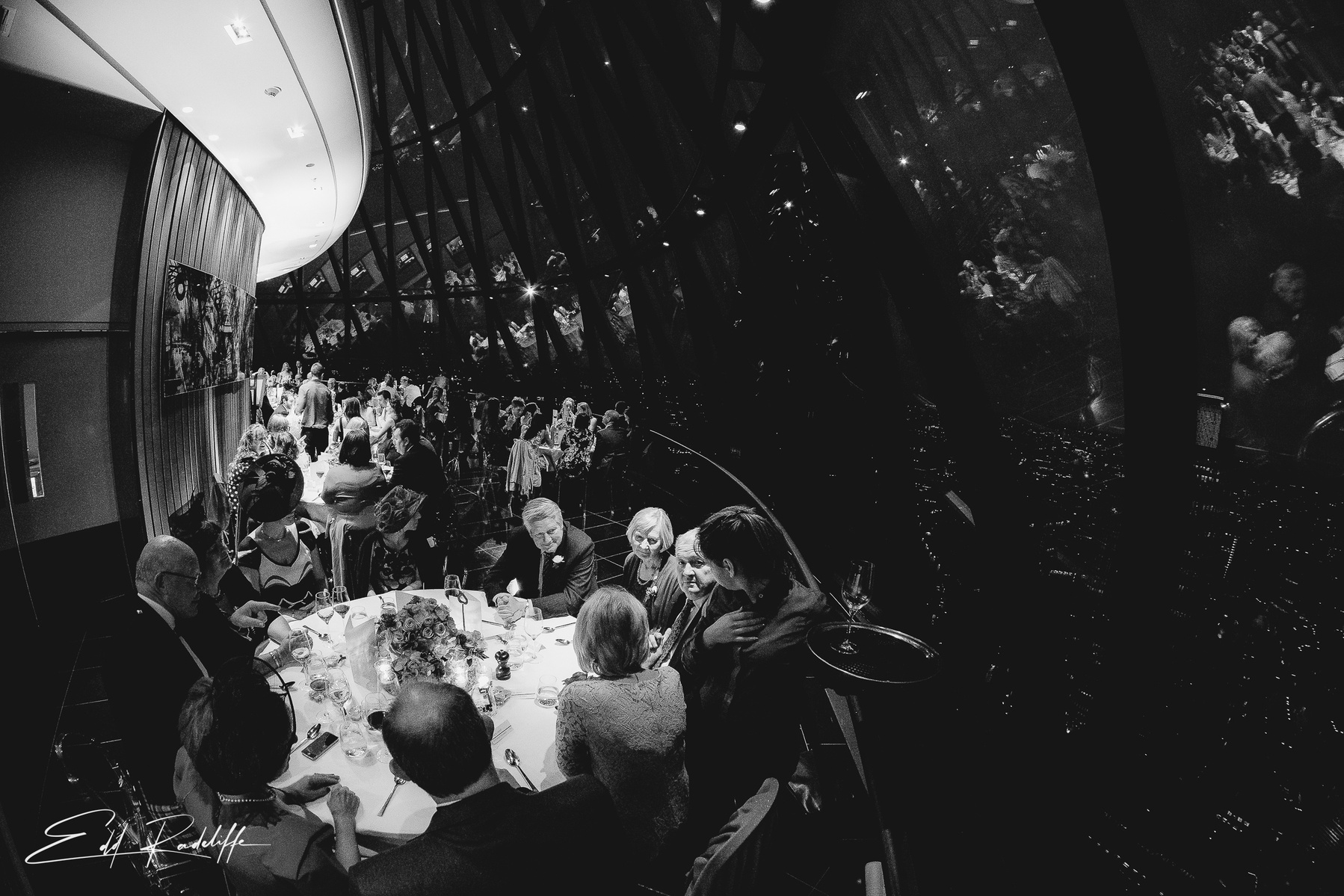 Stunning view of wedding breakfast with backdrop of interior glass windows of St Marys Axe, London for Edd Radcliffe Photography - documentary style wedding photography