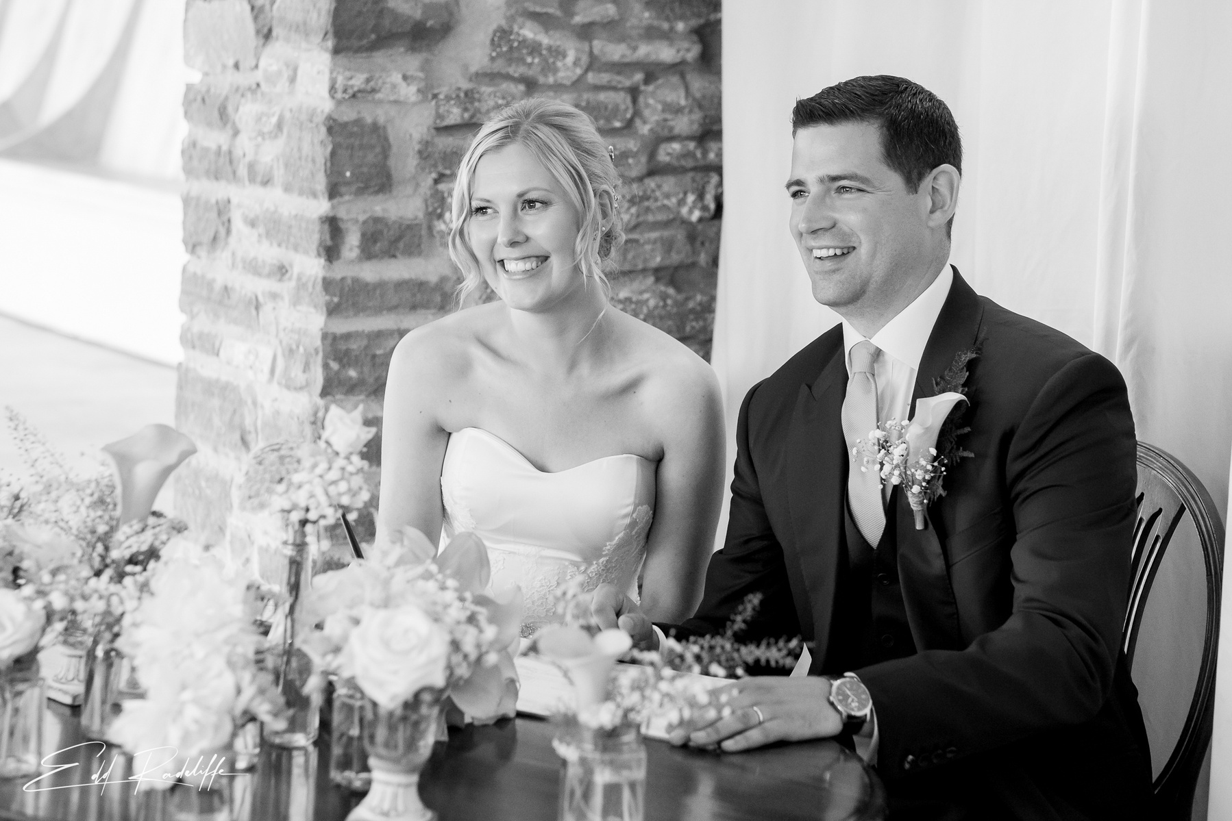 Bride and Groom sit side by side smiling at the signing of the register at Porthmawr Country House in Crickhowell, Wales for Edd Radcliffe Photography - documentary style wedding photography