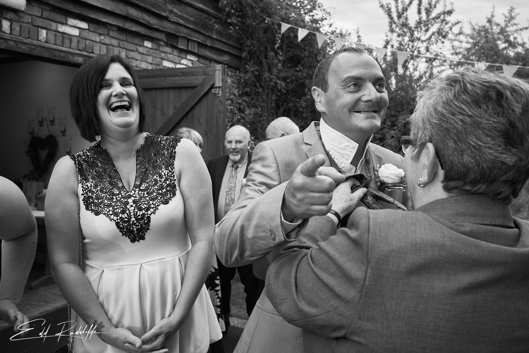 Wedding guest laughs as man is assisted with having his bowtie knotted at The Square and Compass in Somerset for Edd Radcliffe Photography - documentary style wedding photography