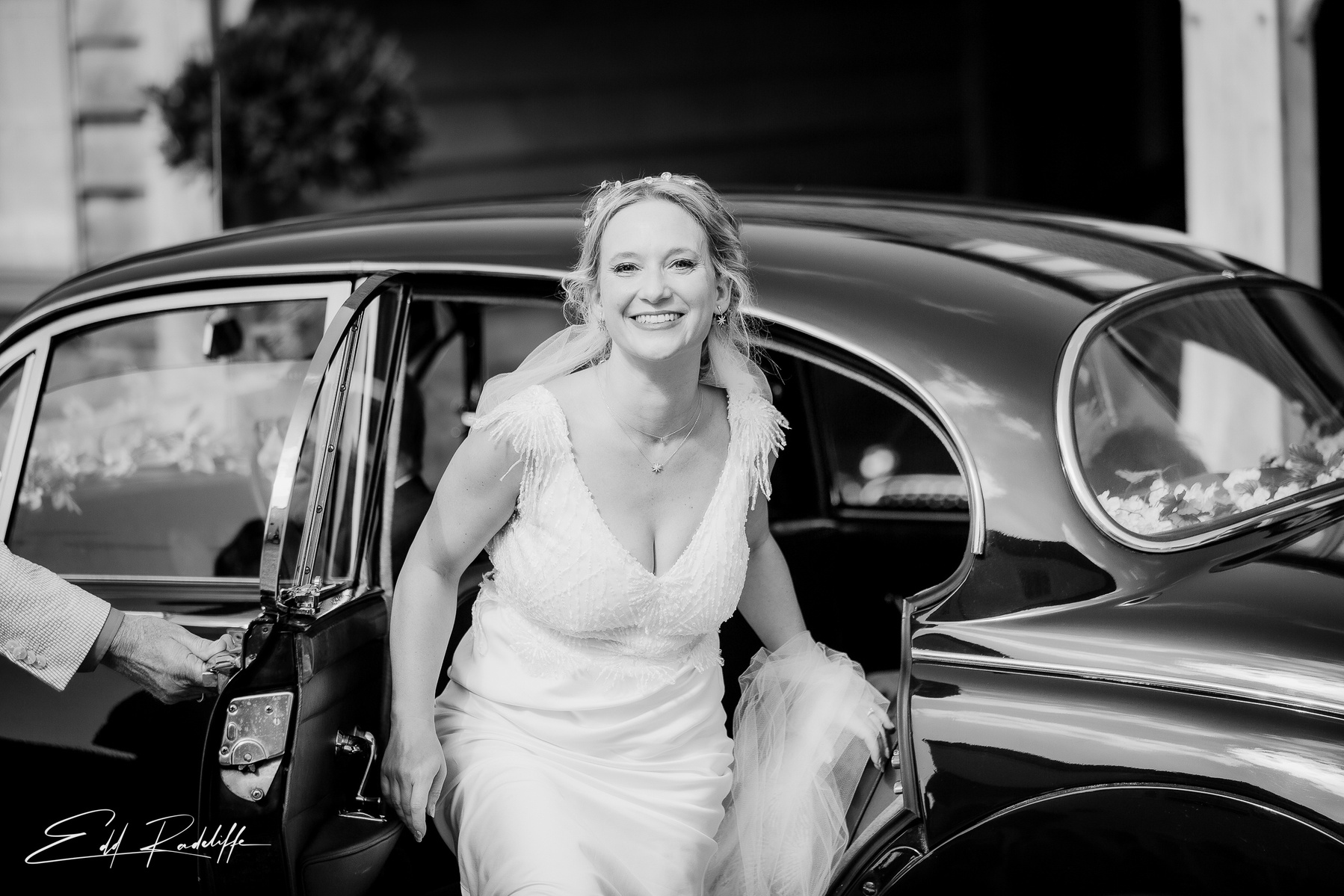 Beaming bride steps out of wedding car at Groomes in Hampshire for Edd Radcliffe Photography - documentary style wedding photography