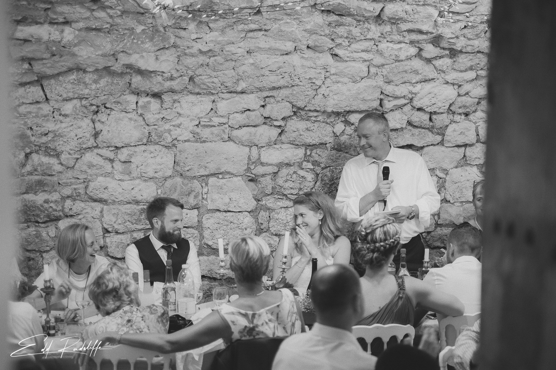 Bride and Groom smile at each other during wedding speeches at Hôtel de Cours de Thomazeau in Castilliones for Edd Radcliffe Photography - documentary style wedding photography