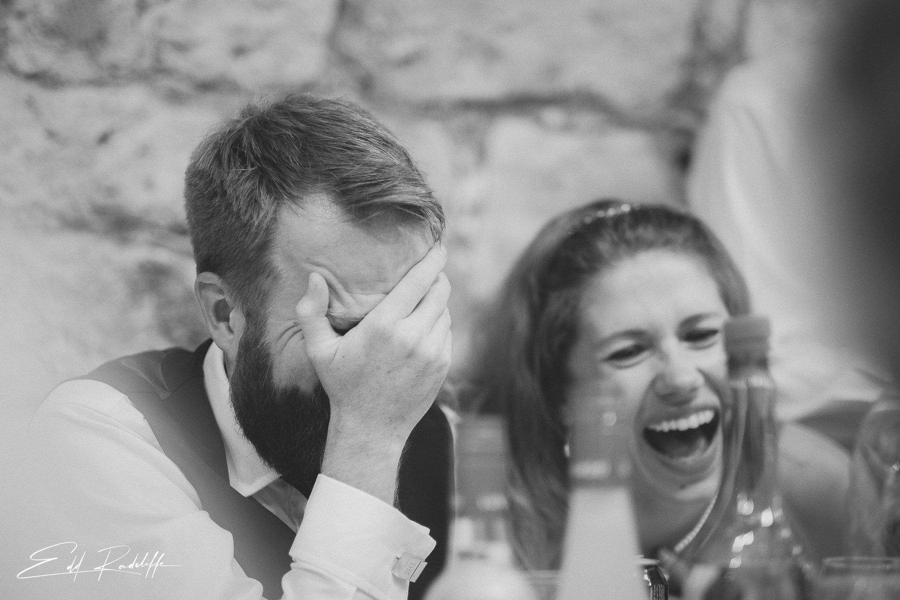 Bride laughs as Groom covers face in laughter during wedding speeches at Hôtel de Cours de Thomazeau in Castilliones for Edd Radcliffe Photography - documentary style wedding photography