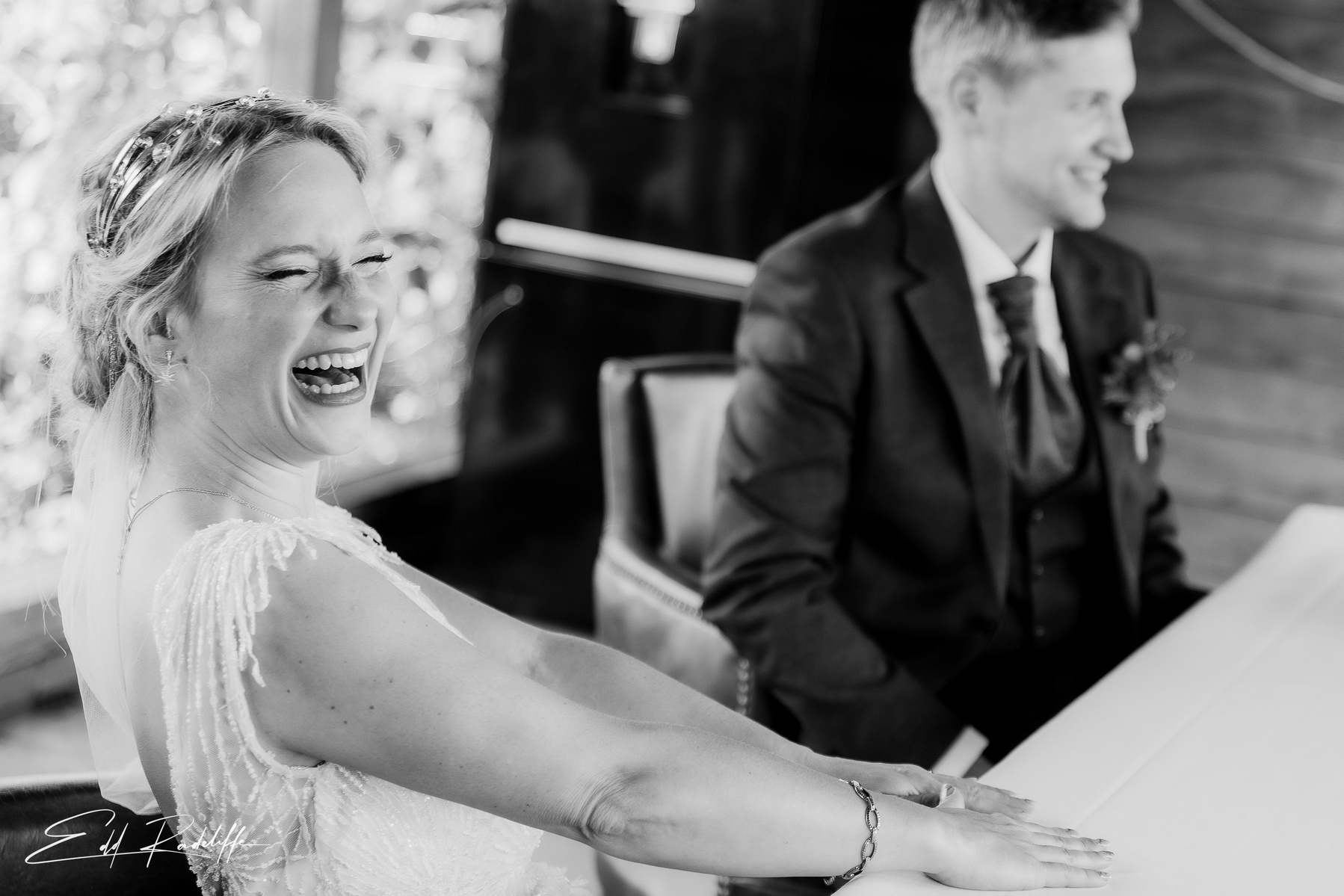 Bride laughs happily at the signing of the register at Groomes in Hampshire for Edd Radcliffe Photography - documentary style wedding photography