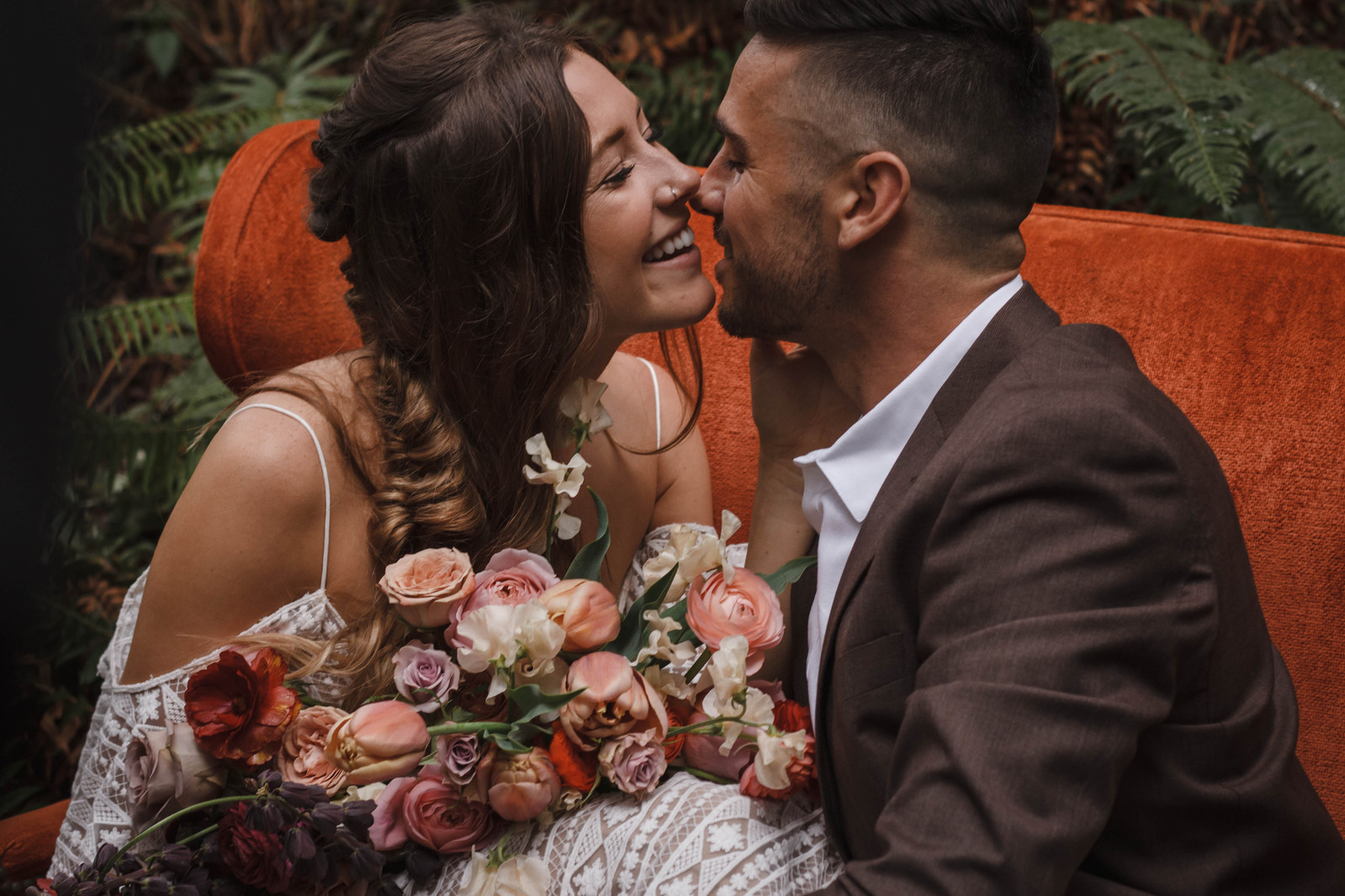 Bride holding flowers and Groom in an elopement outfit kiss in Mt Hood National Forest.