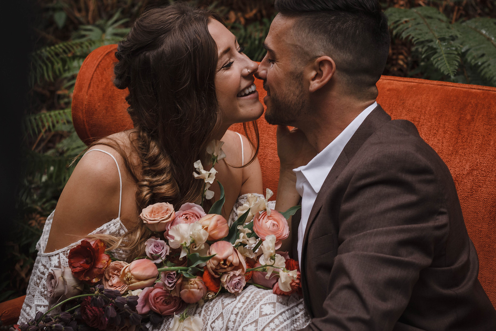 Bride holding flowers and Groom in an elopement outfit kiss in Mt Hood National Forest.