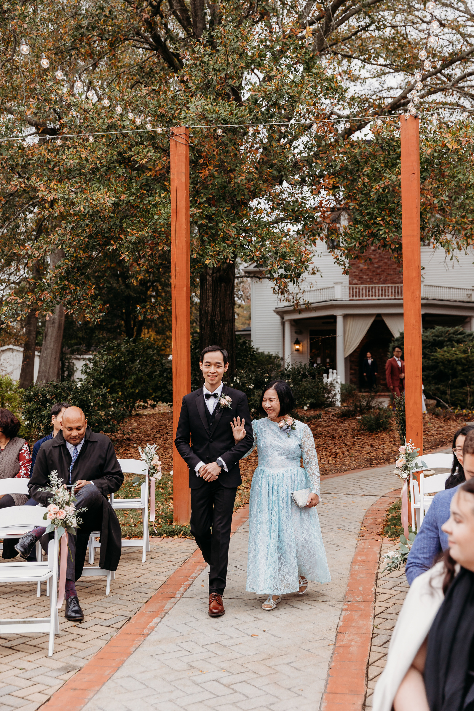 groom being escorted down the aisle by his mom