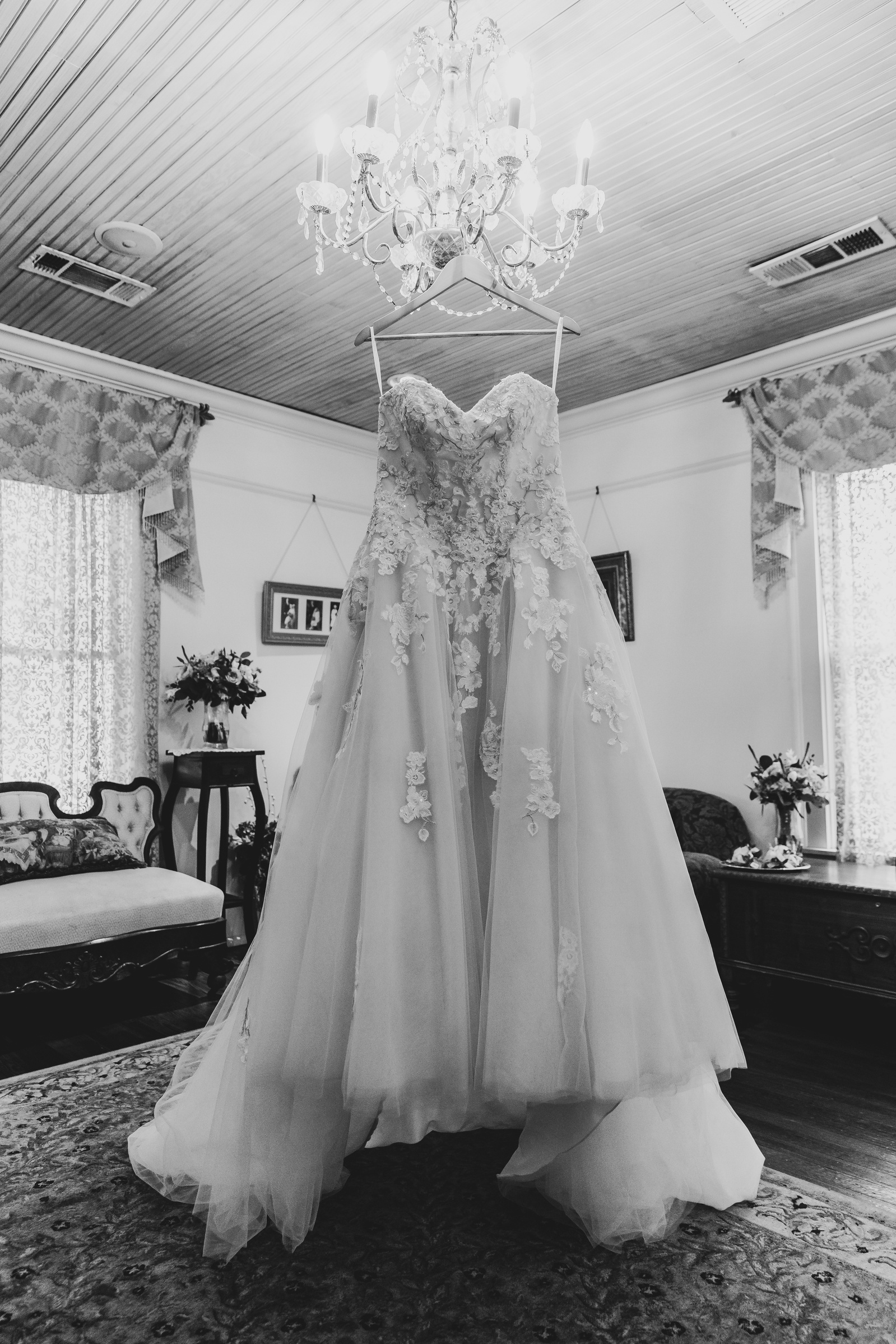 black and white image of a dress hanging from a chandelier