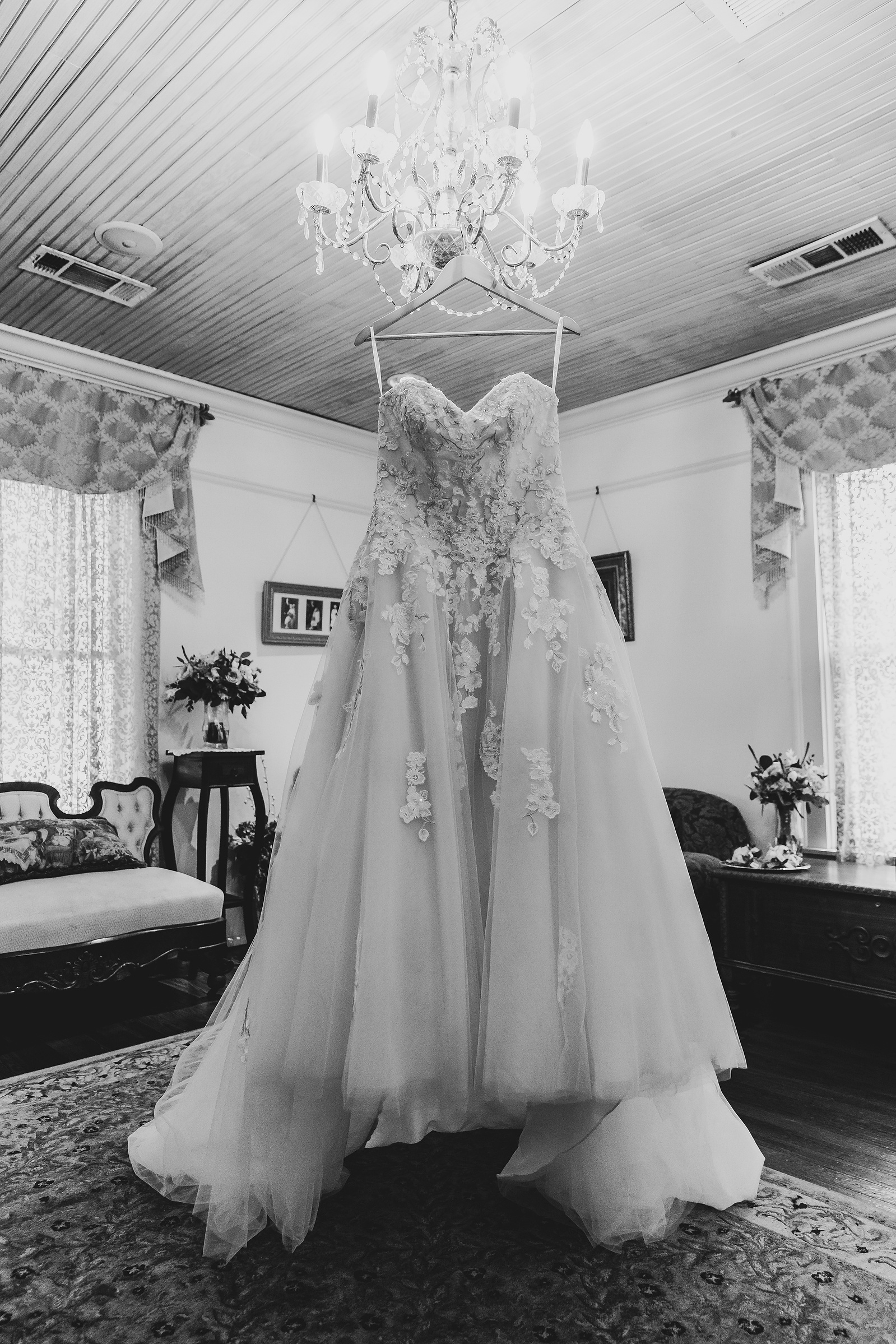 black and white image of a dress hanging from a chandelier