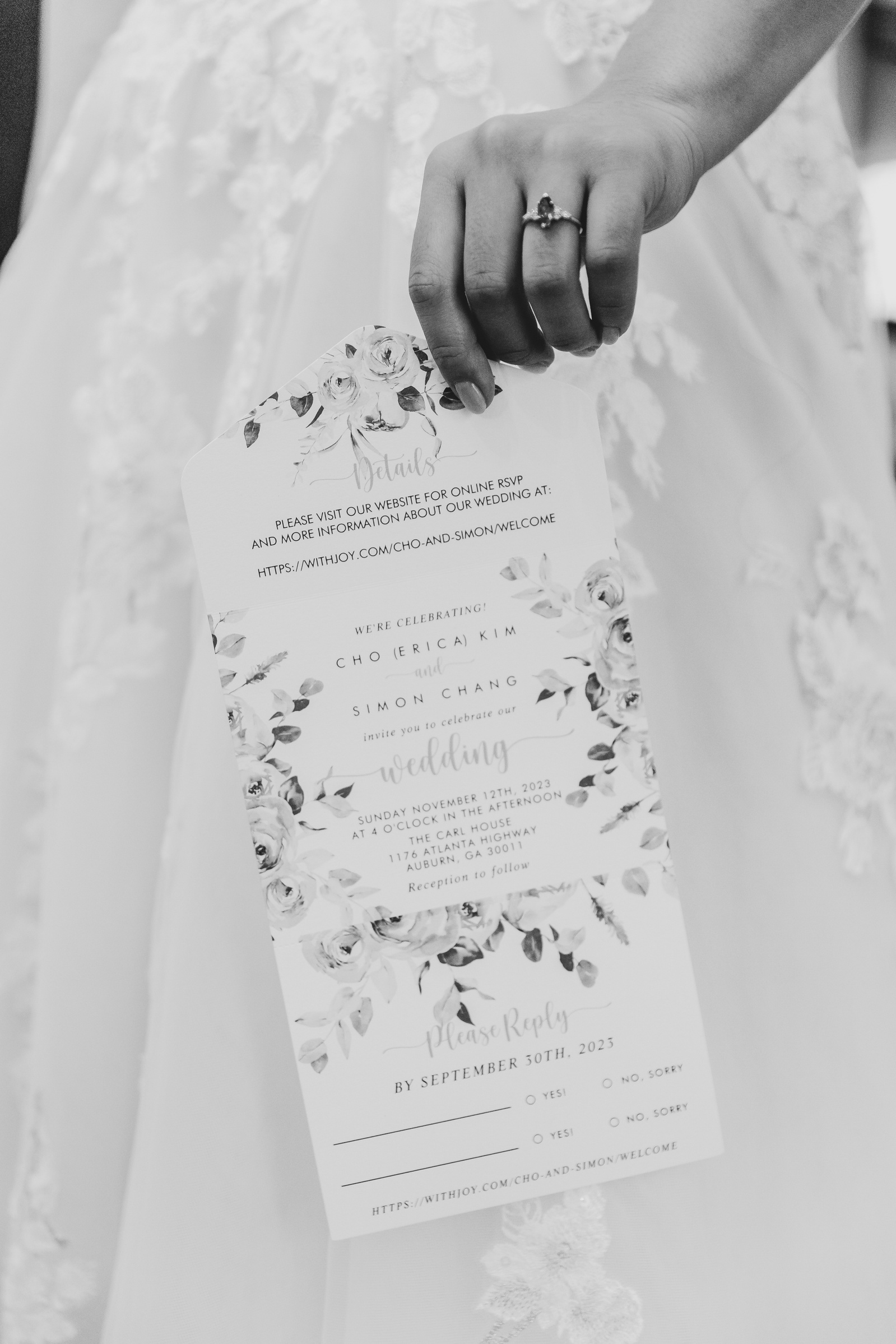 black and white image of a brides hand holding her wedding invitation