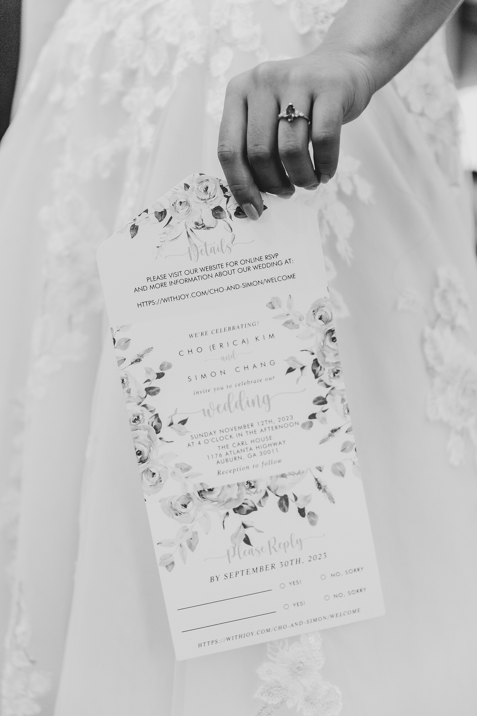 black and white image of a brides hand holding her wedding invitation