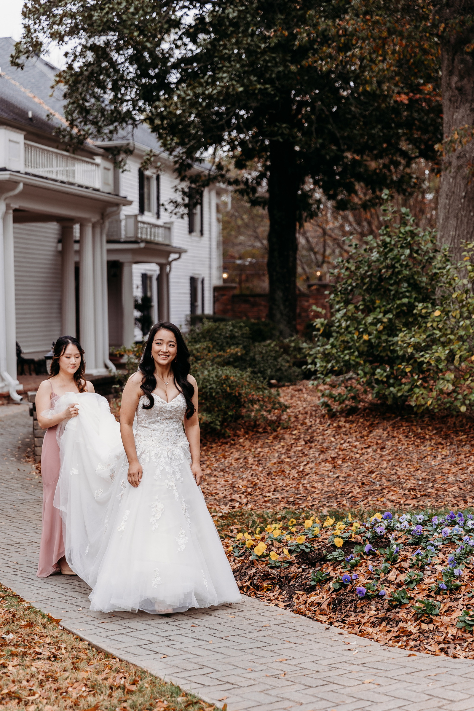 bridesmaid holding up the brides wedding dress as she walks towards her first look