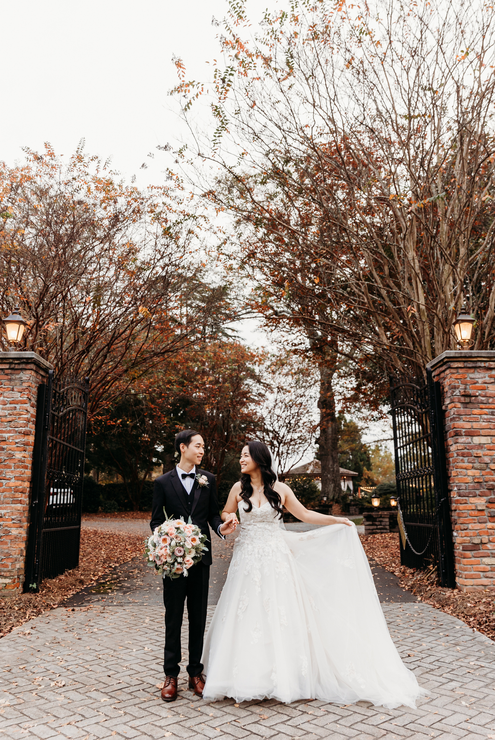 groom holding the brides flowers, bride is holding her dress