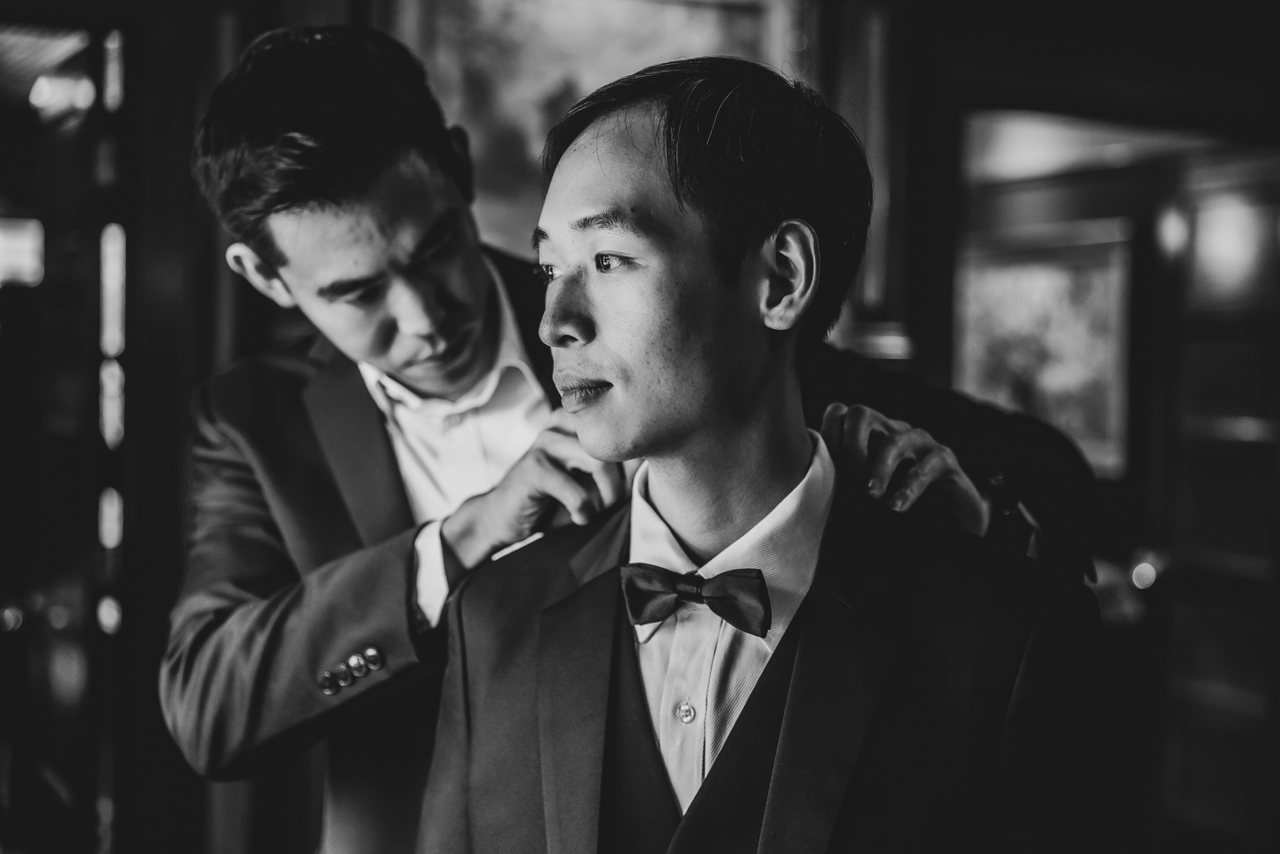 black and white image of the best man adjusting the grooms tie