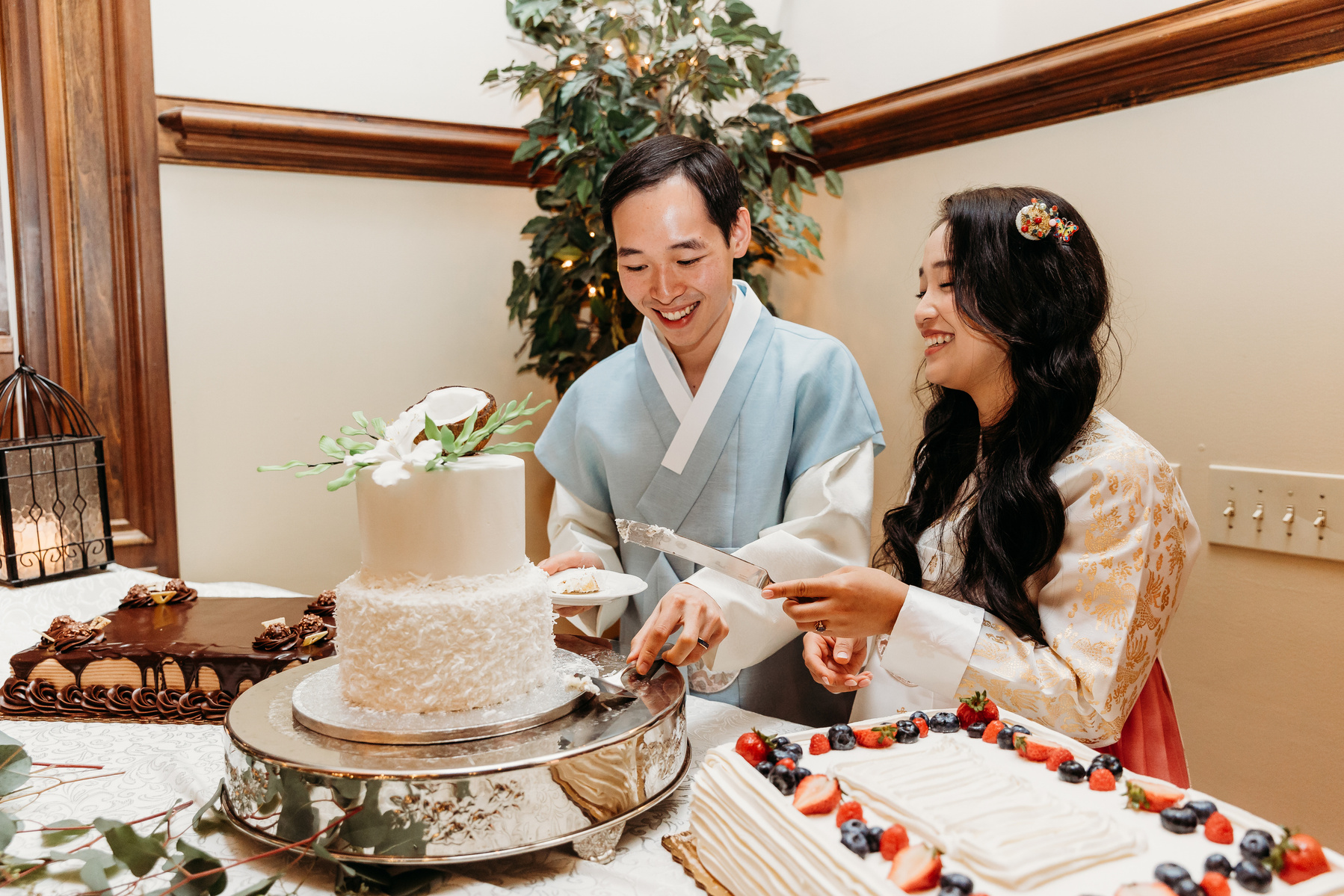 bride and groom cutting cake while wearing traditional hanbok