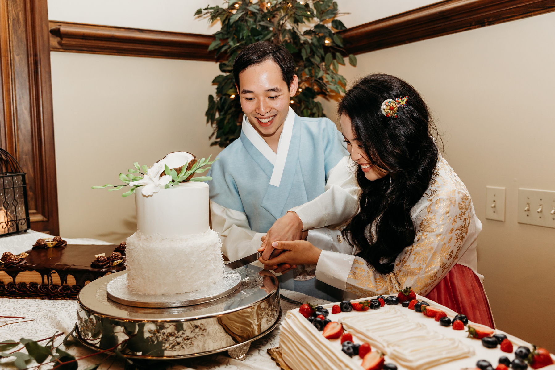 bride and groom cutting cake while wearing traditional hanbok