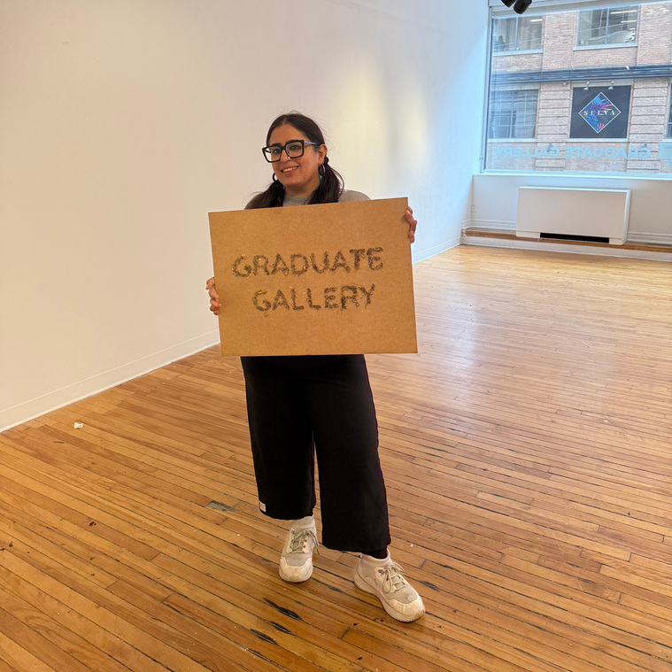 Deepikah RB holding a sign made with leaves, nori paste and soil. The sign reads - Graduate Gallery. 