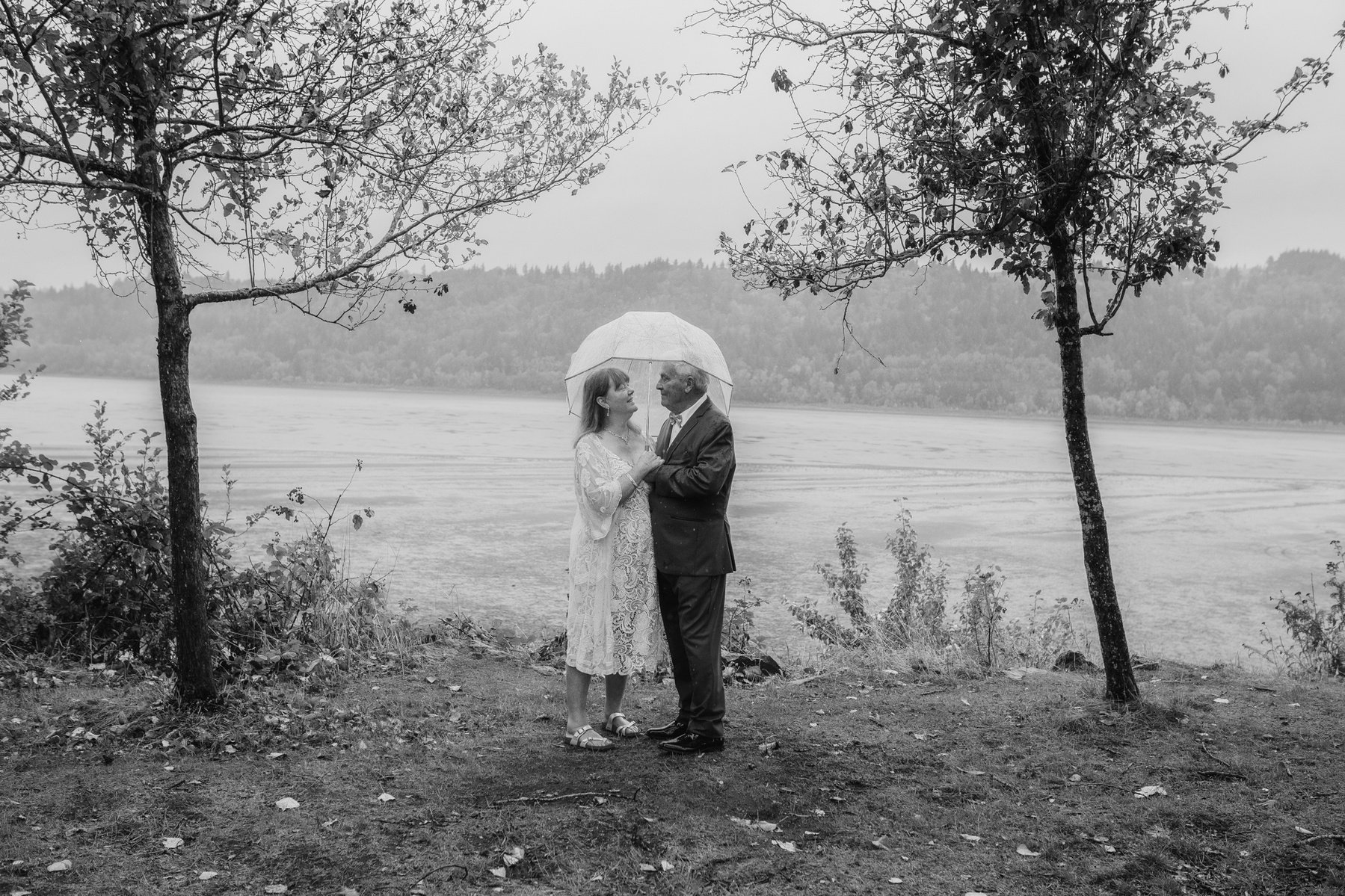 An older couple standing in a sweet embrace after their rainy-day elopement ceremony on the Columbia River Gorge.