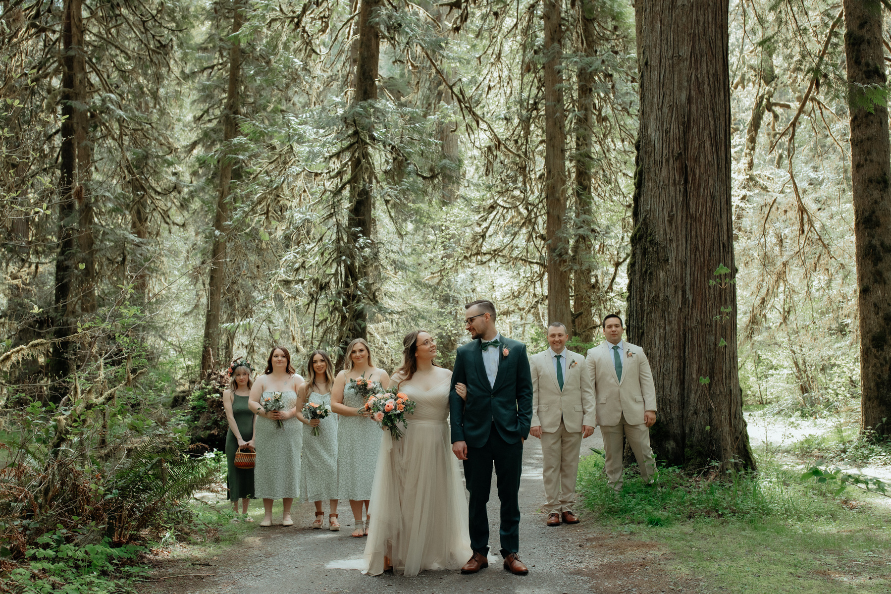 A couple standing in front of their wedding party in a beautiful forest located in the Pacific Northwest.