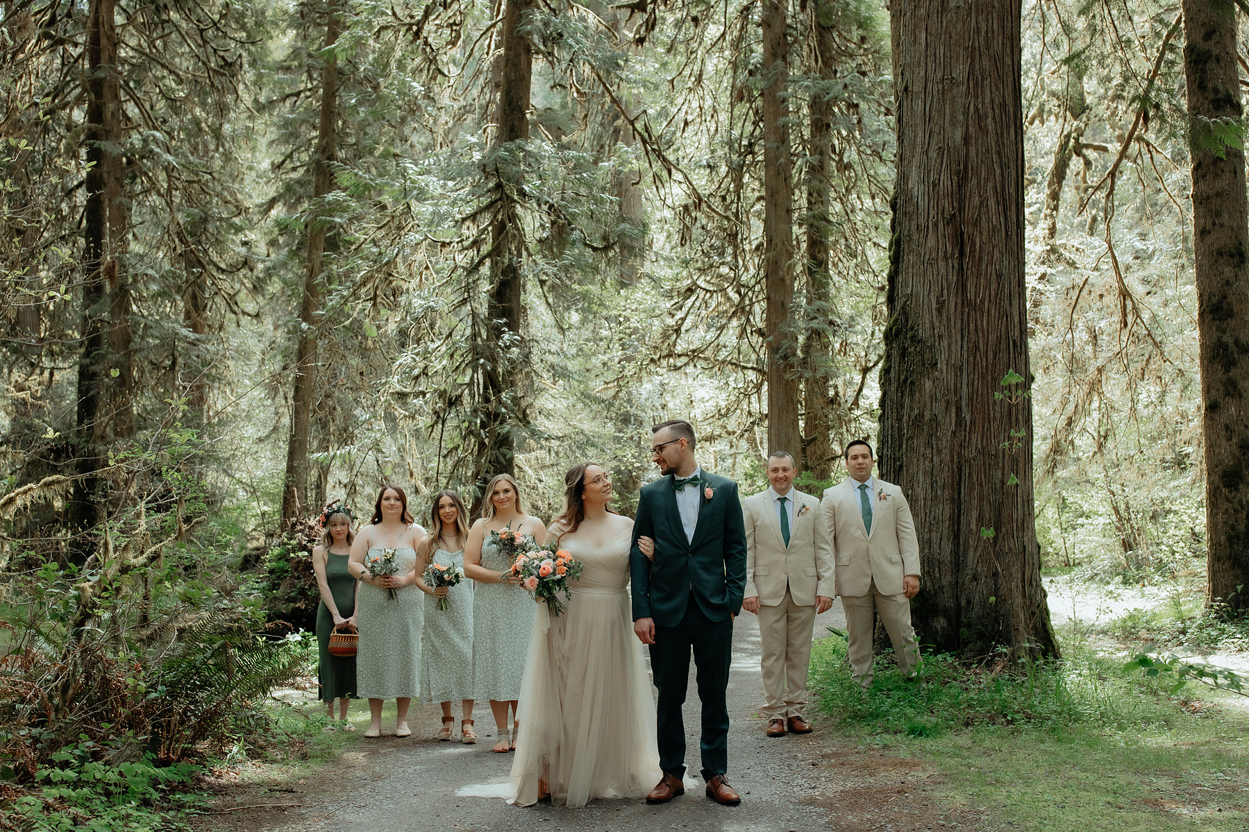 A couple standing in front of their wedding party in a beautiful forest located in the Pacific Northwest.