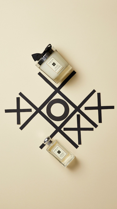 A playful and visually engaging composition featuring two perfume bottles strategically placed on a Tic-tac-toe game board. This creative image is skillfully photographed by David Lineton, an expert in perfume photographer