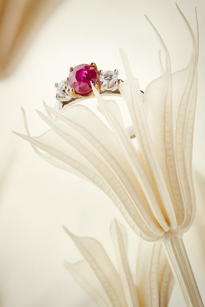 A delightful composition featuring a ring with a pink stone gracefully placed on a flower sculpture. This visually appealing scene is skillfully photographed by David Lineton, an expert in jewelry photography services in London.