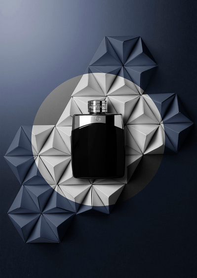A sleek composition featuring a perfume bottle placed on a surface with a dark gray color, elegantly positioned within a white circle. This sophisticated image is skillfully captured by David Lineton, an expert in perfume commercial photography in London.