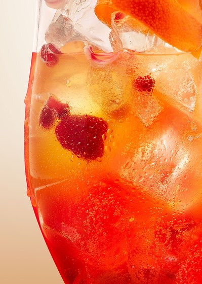 A close-up capture of an orange drink inside a glass with ice pieces, showcasing the vibrant colors and refreshing details. This visually engaging image is skillfully photographed by David Lineton, an expert in drink product photography in London