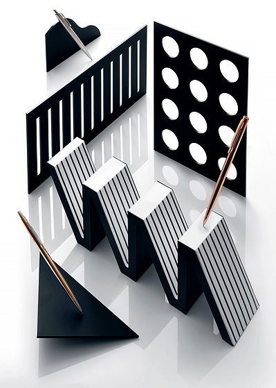 A creatively composed scene featuring two pens, one on a black surface and the other on a zigzag-type surface. This imaginative arrangement is expertly captured by David Lineton, a distinguished creative product photographer in London.