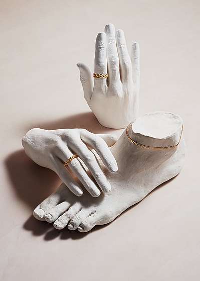 A creative and artistic photograph capturing the beauty of jewelry on two cut white hands and one foot. This visually compelling composition is skillfully photographed by David Lineton, an expert in commercial jewelry photography in London