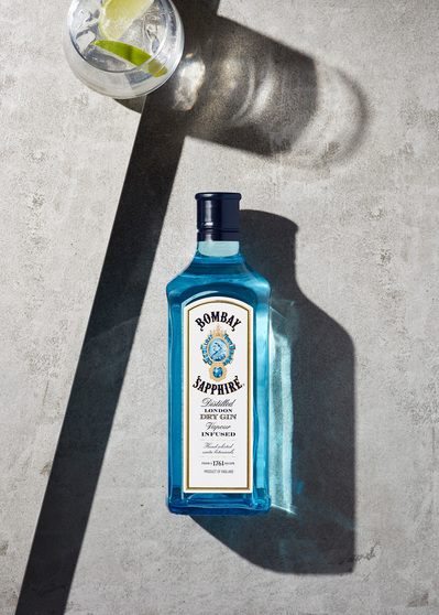 A captivating top-down photograph featuring the Bombay Sapphire bottle alongside a glass filled with the drink and topped with a slice of lemon. Captured by David Lineton, an expert in commercial drinks photography in London