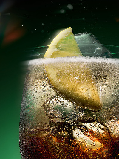 A close-up photograph capturing the refreshing details of a cold drink, with ice and a lemon on top.  This refreshing image is skillfully photographed by David Lineton, an expert in drinks photography in London. 