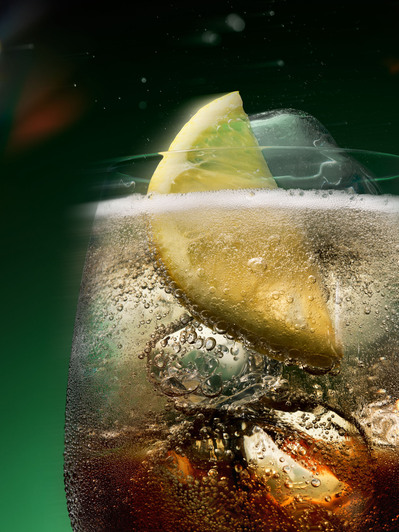 A close-up photograph capturing the refreshing details of a cold drink, with ice and a lemon on top.  This refreshing image is skillfully photographed by David Lineton, an expert in drinks photography in London. 