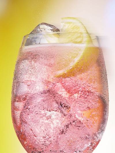 A refreshing composition capturing a glass of drink filled with ice, adorned with a lemon slice on top. This invigorating image is skillfully photographed by David Lineton, an expert in drinks photography in London. 