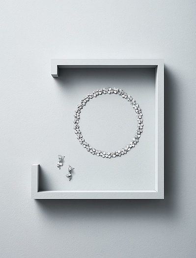 A stylish arrangement featuring two earrings and a round necklace elegantly placed inside an open box, covered from three sides. This skillfully crafted image is captured by David Lineton, an expert in luxury product photography in London