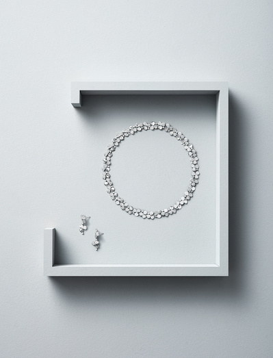A stylish arrangement featuring two earrings and a round necklace elegantly placed inside an open box, covered from three sides. This skillfully crafted image is captured by David Lineton, an expert in luxury product photography in London