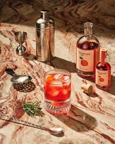 An enticing composition showcasing Negroni drinks arranged alongside a glass filled with the beverage. This visually appealing scene is skillfully photographed by David Lineton, an expert in commercial drinks photography in London.